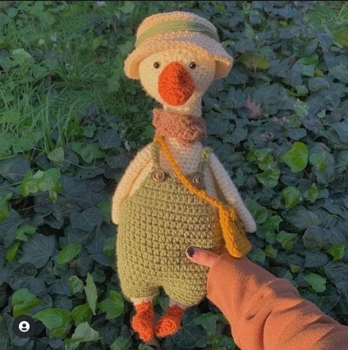 a crocheted stuffed animal is being held by someone's hand in the grass