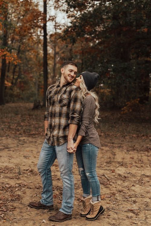 a man and woman standing together in the woods with their hands on each other's hips