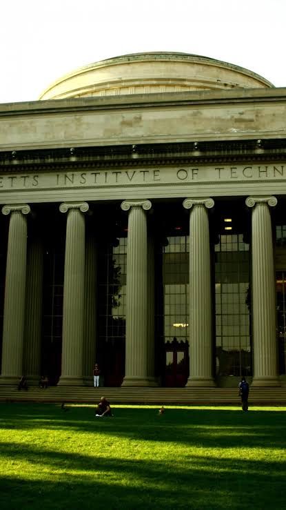 people sitting on the grass in front of a large building with columns and letters that read, masters institute of technology