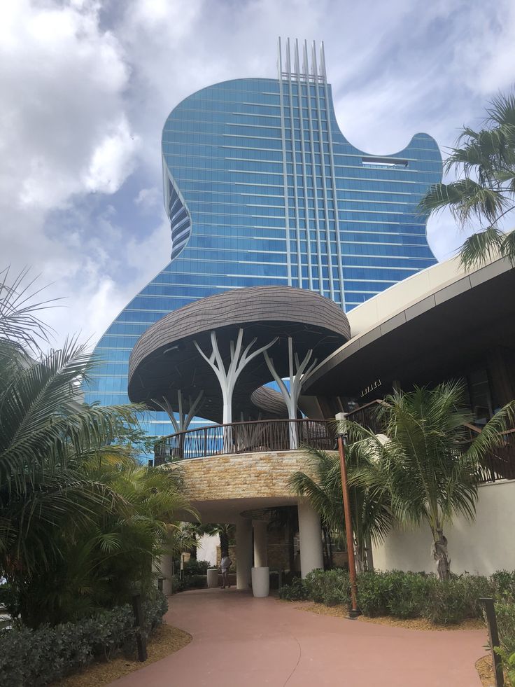 a large guitar shaped building with palm trees in the foreground and a walkway leading up to it