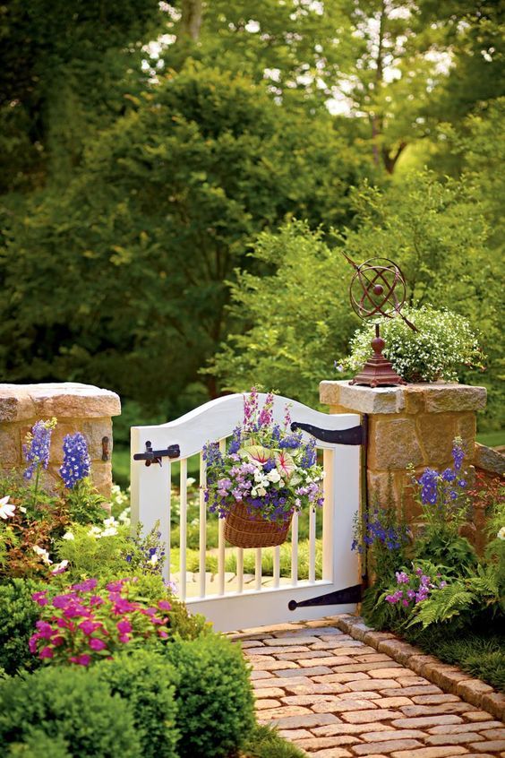 a white gate with flowers and plants in it