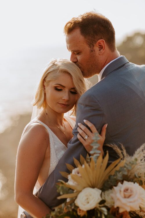 a bride and groom embracing each other in front of the ocean