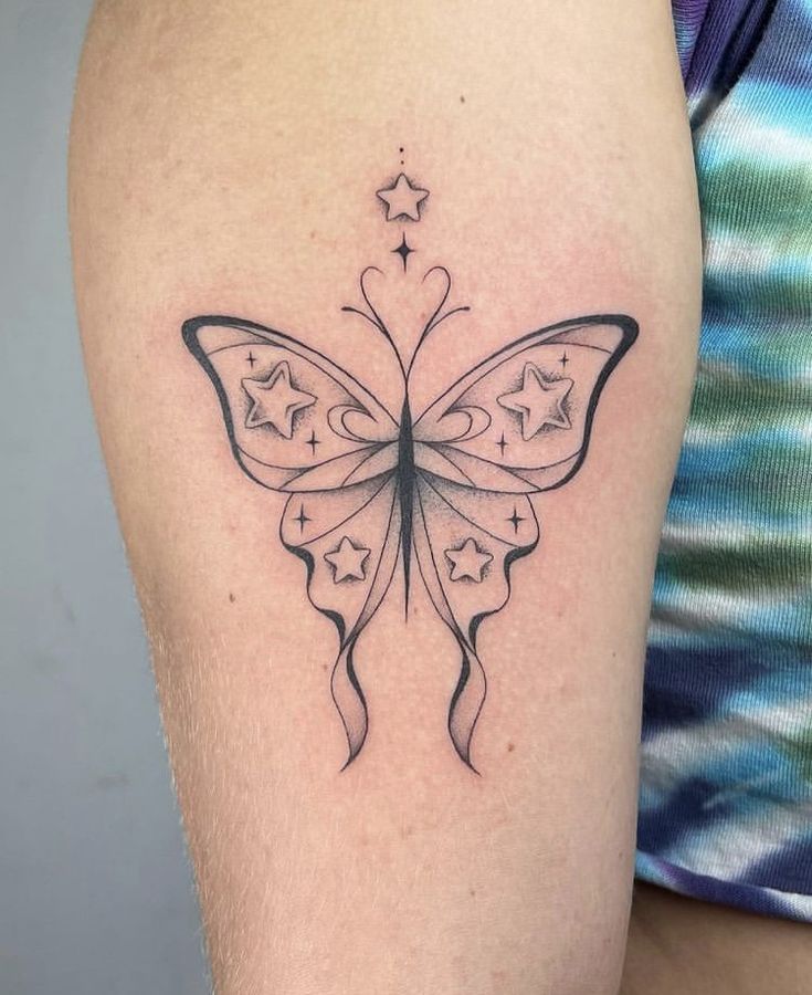 a black and white butterfly tattoo on the right thigh, with stars in the back