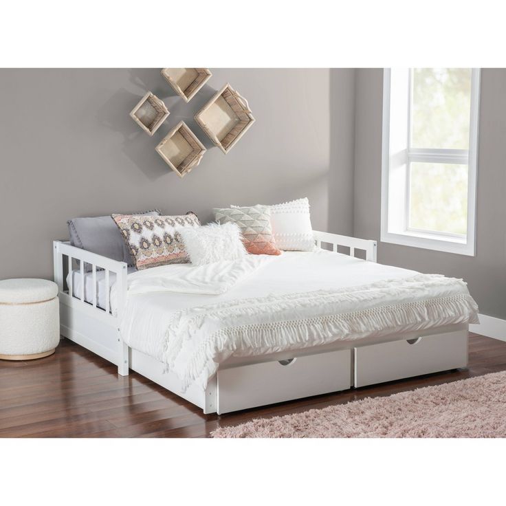 a white bed sitting on top of a hard wood floor next to a large window