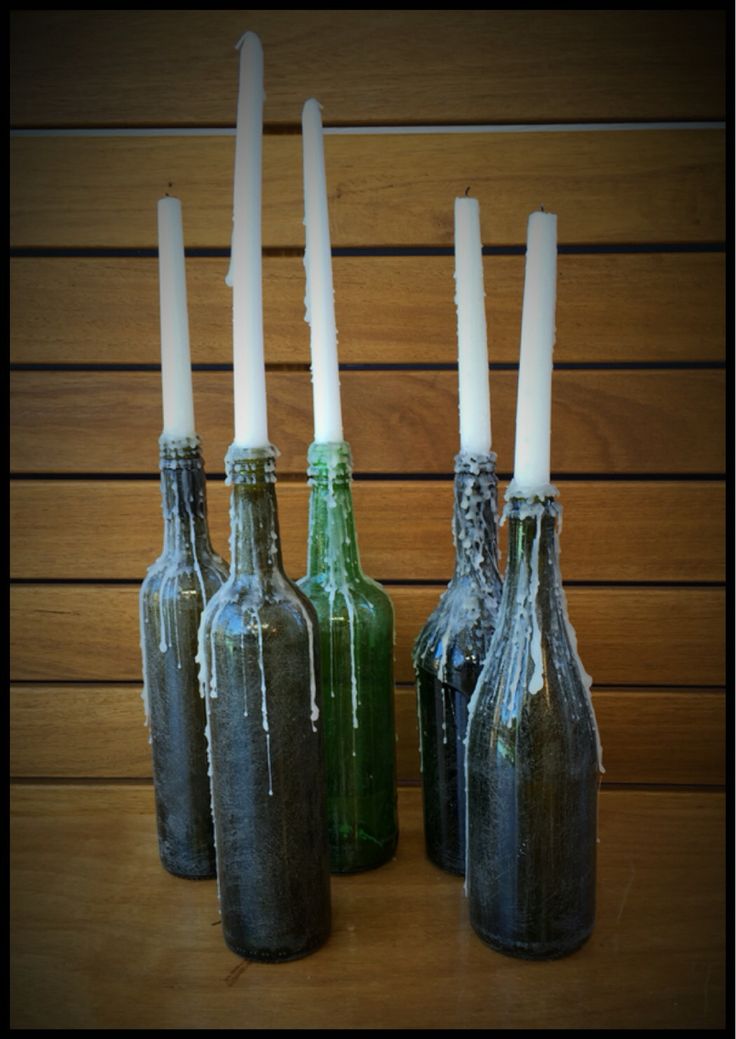 four empty bottles with candles in them sitting on a table