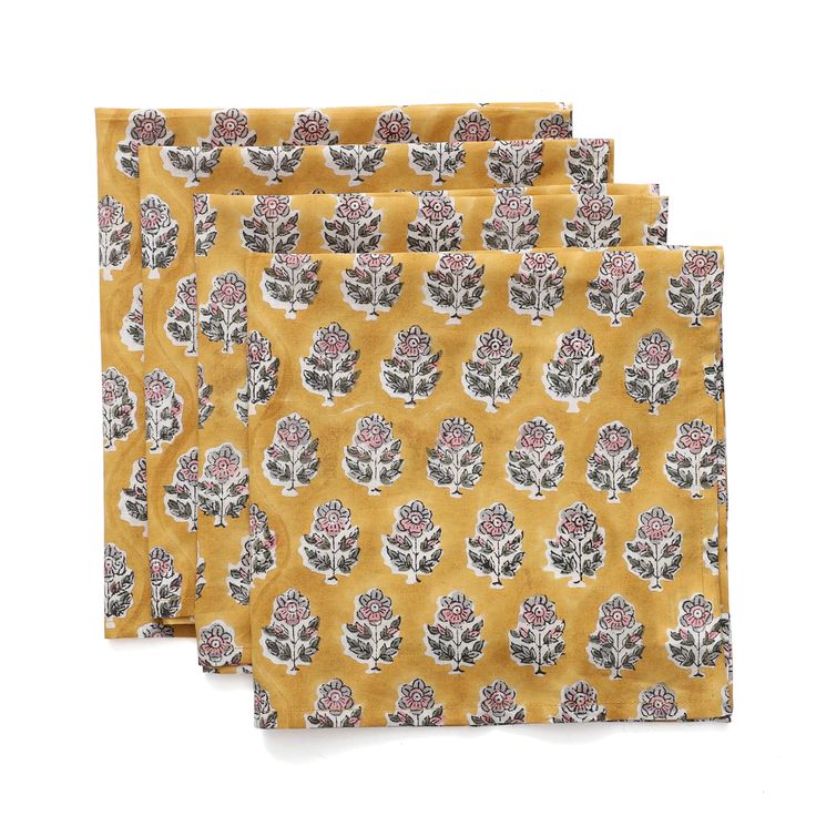 three napkins with trees on them in yellow and grey colors, one has a red flower