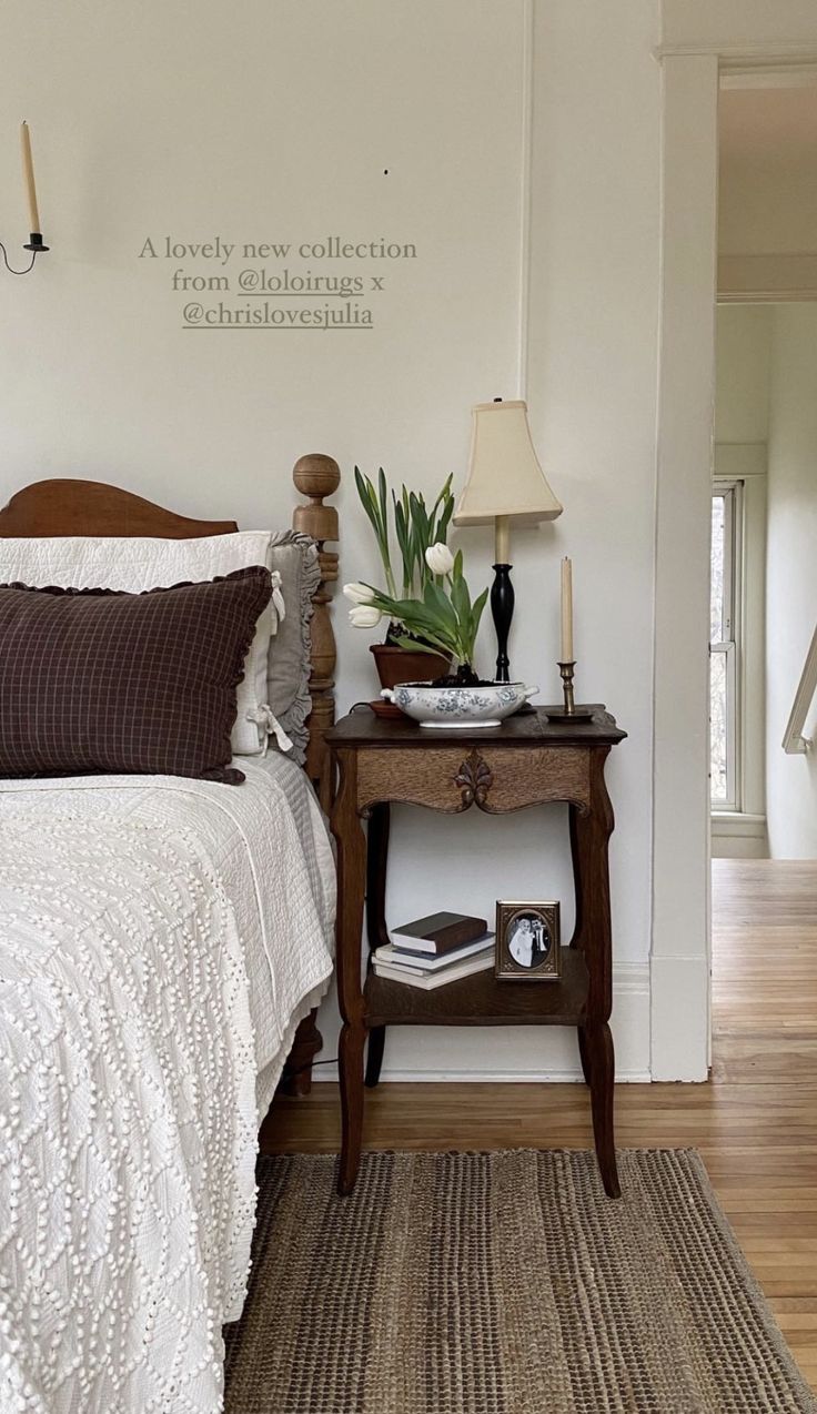 a bedroom with a bed, nightstand and lamp on the side table in front of it