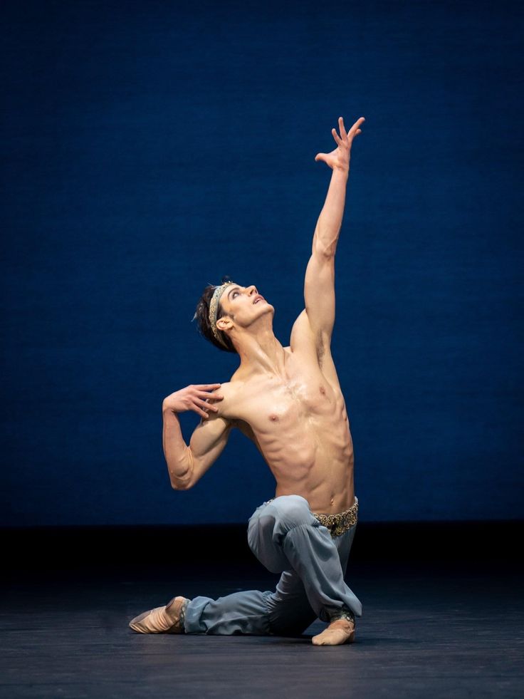 a man in grey pants and no shirt is doing a dance pose on the floor