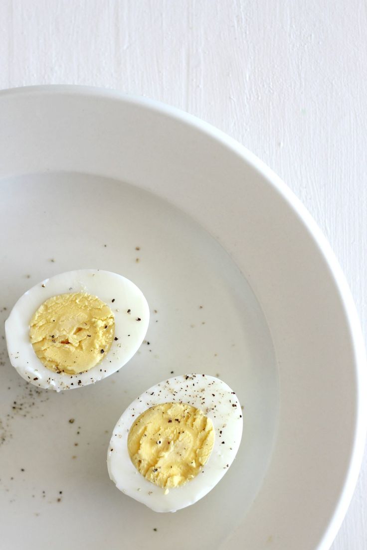 two hard boiled eggs on a plate with mustard and seasoning sprinkles