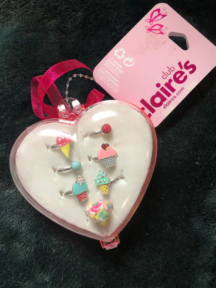 a white heart shaped box with pins in it and a pink ribbon on the side