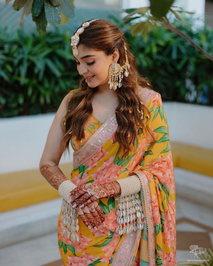 a woman in an orange and yellow sari is holding her hands on her hip