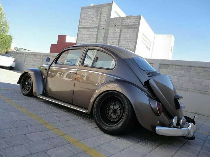 an old vw bug is parked on the street