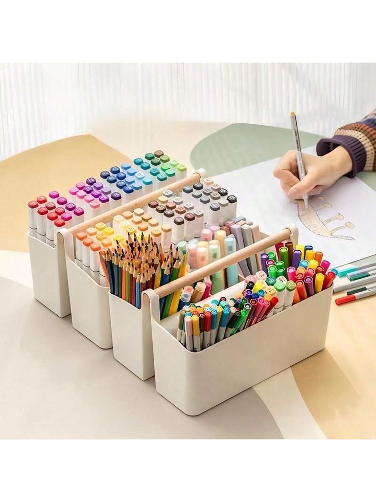 a person is sitting at a table with many different colored pencils and crayons