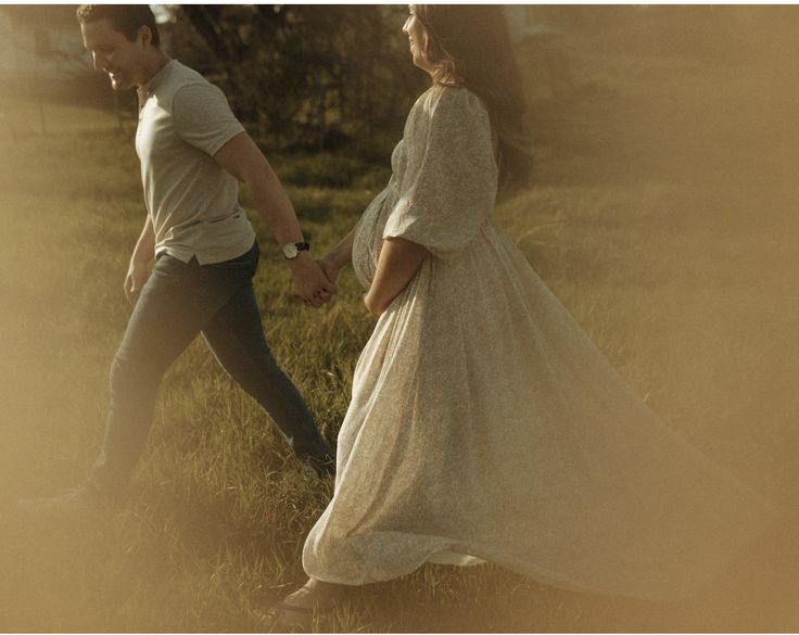 two people are walking in the grass holding hands