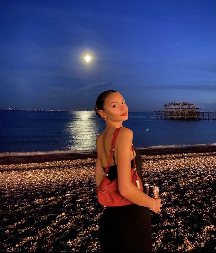 a woman is standing on the beach at night