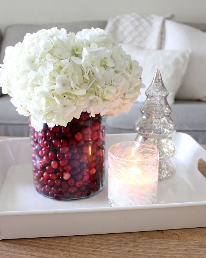 a glass vase filled with white flowers on top of a tray next to a candle