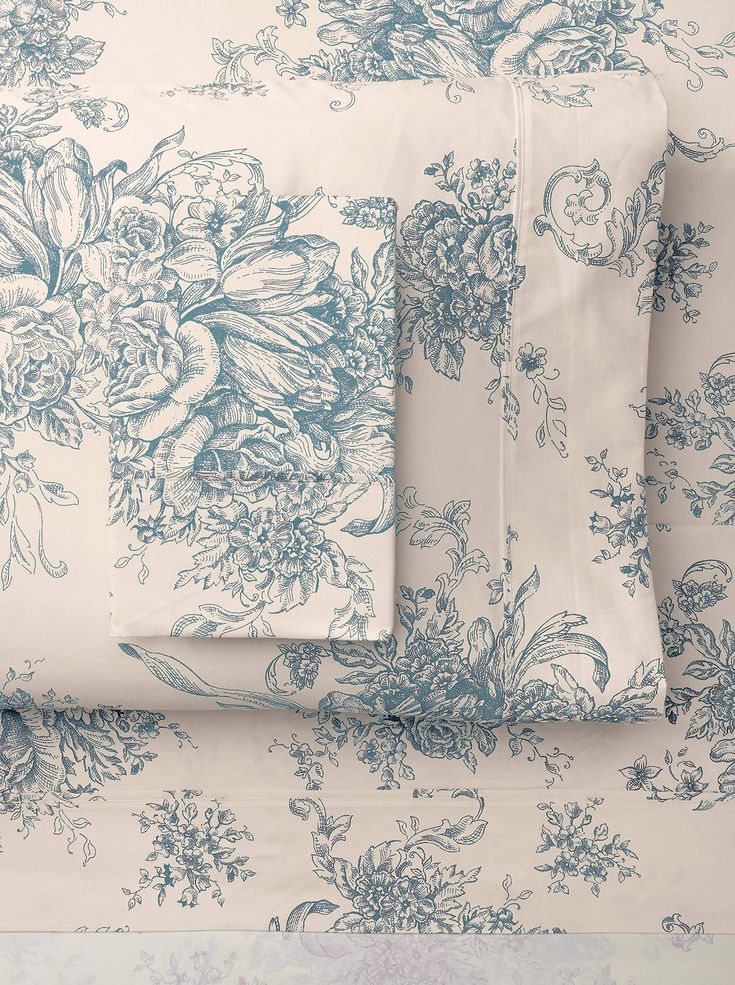 the blue and white floral bedding is neatly arranged on top of each other,