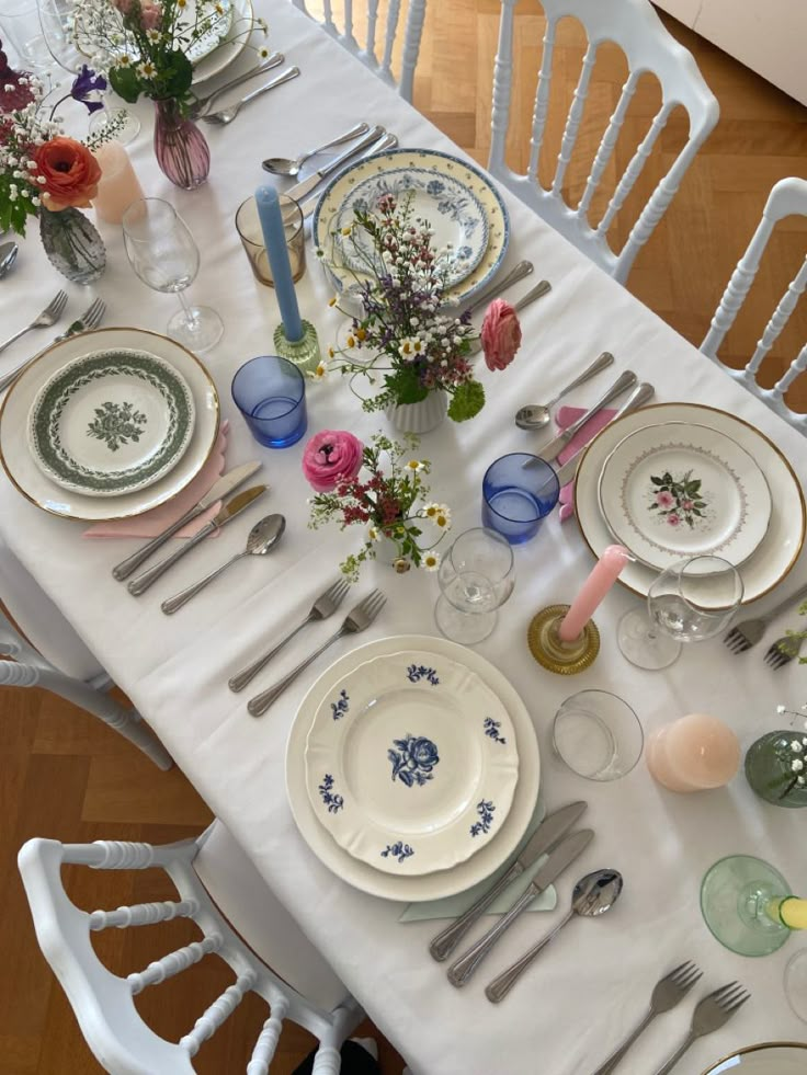 the table is set with plates, silverware and flowers in vases on it