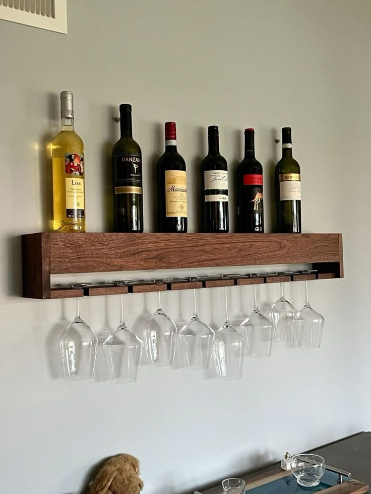 a teddy bear is sitting on a table with wine glasses and bottles in front of it