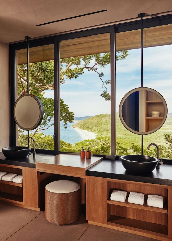 a bathroom with two sinks and large windows looking out onto the ocean in front of it