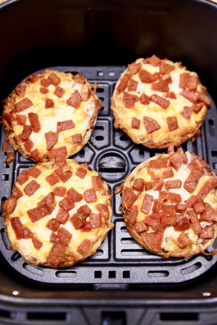 four mini pizzas sitting on top of an air fryer