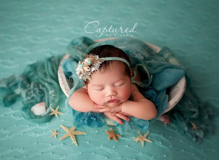 a baby is laying down with her hands on her chest and wearing a headband