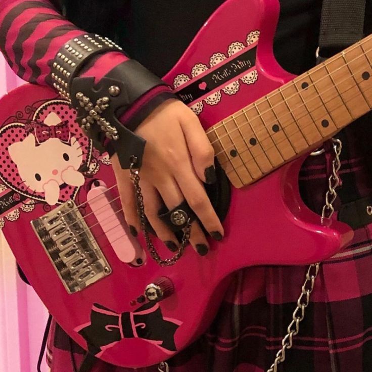 a person in a skirt holding a pink guitar with hello kitty decorations on it's body