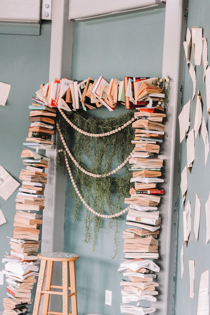 there are many books on the wall next to a stool and table with papers all over it