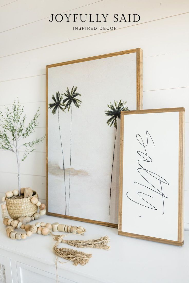 a white mantle with two framed palm trees on it and a sign that says joyfully said