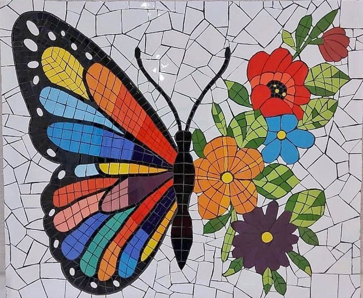 a colorful butterfly sitting on top of a white tile wall with flowers and leaves painted on it