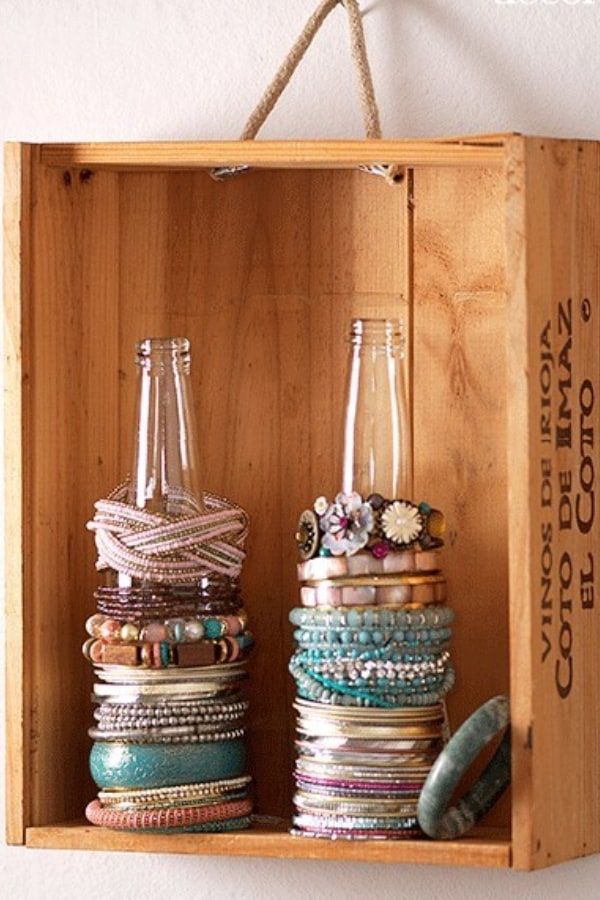 a wooden box filled with lots of different types of bracelets and glass vases