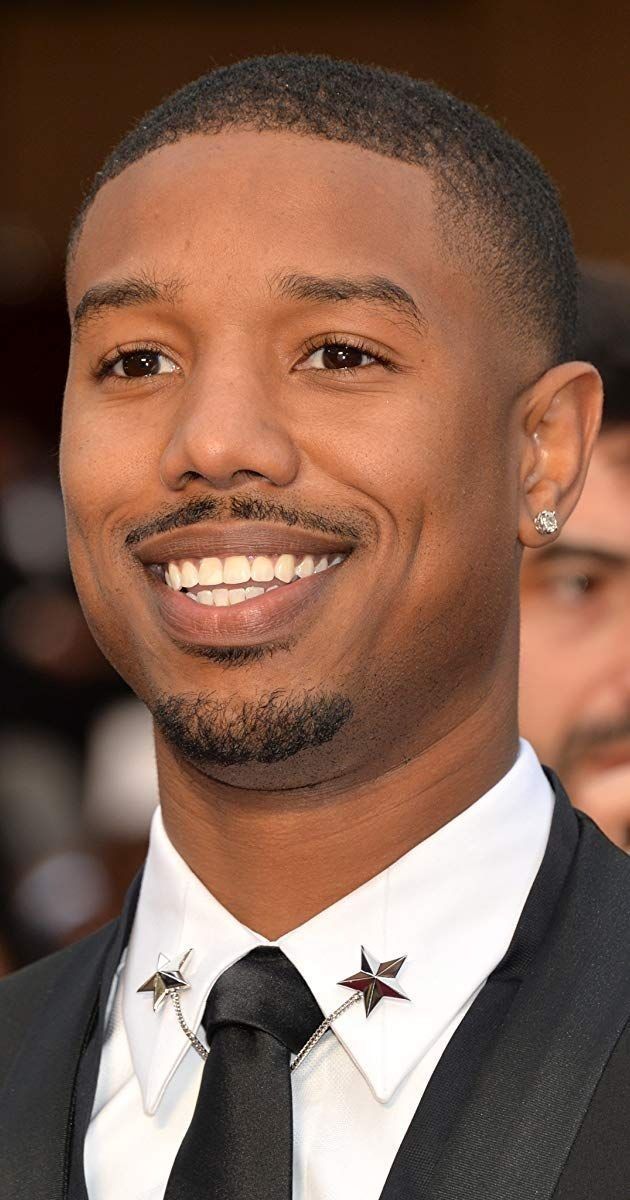 a close up of a person wearing a suit and tie with stars on his lapel