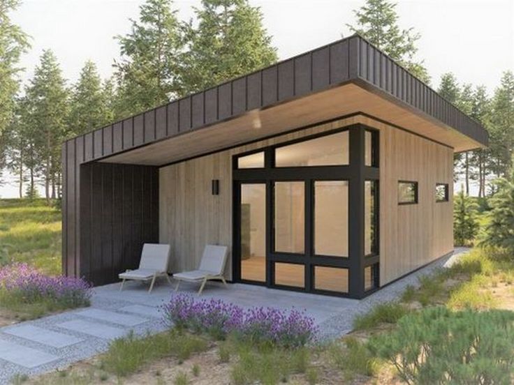 a small wooden cabin in the middle of a field with purple flowers and trees around it