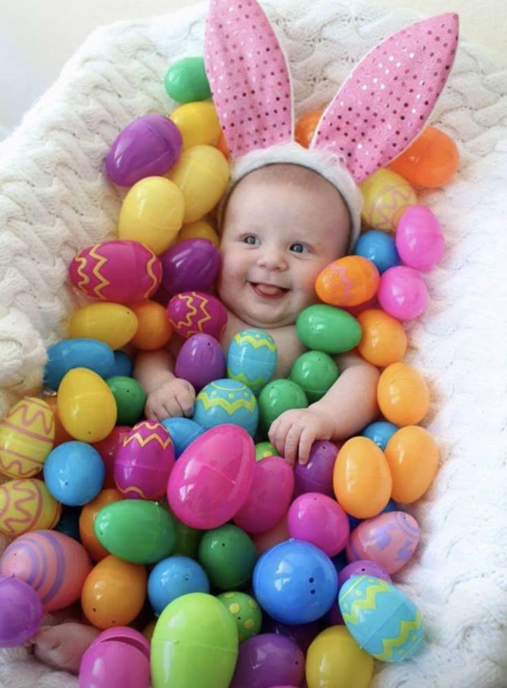 a baby sitting in a basket filled with easter eggs