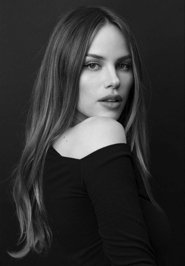 a black and white photo of a woman with long hair wearing a off the shoulder top