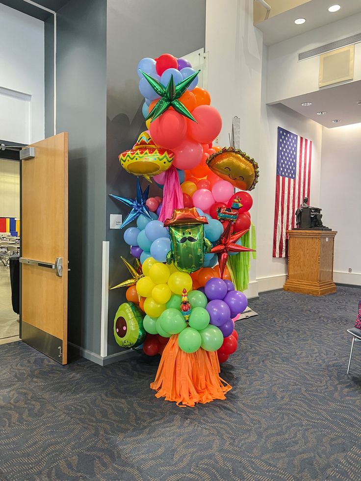 a large balloon tree in an office lobby with balloons all over the top and around the base