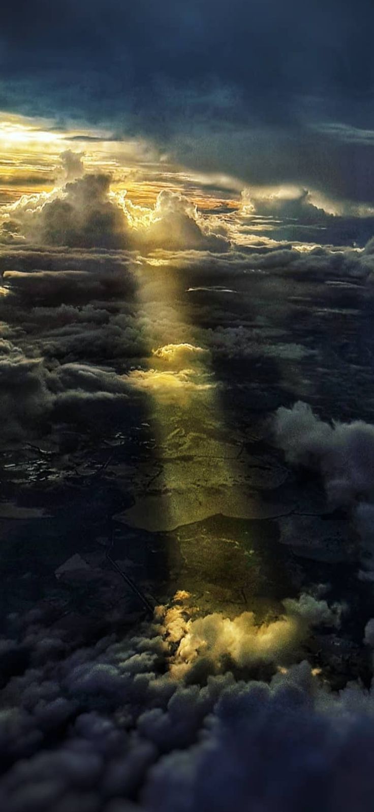 the sun is shining through clouds in the sky over water and land, as seen from an airplane window