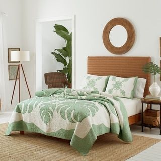 a bed with green and white bedspread in a bedroom next to a mirror