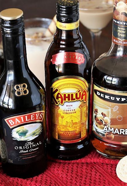 three different types of alcohol sitting on top of a red table cloth next to glasses