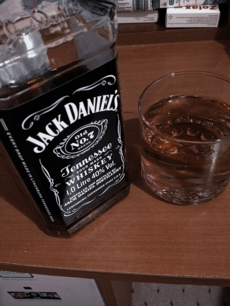 a bottle of jack daniels next to a glass on a table