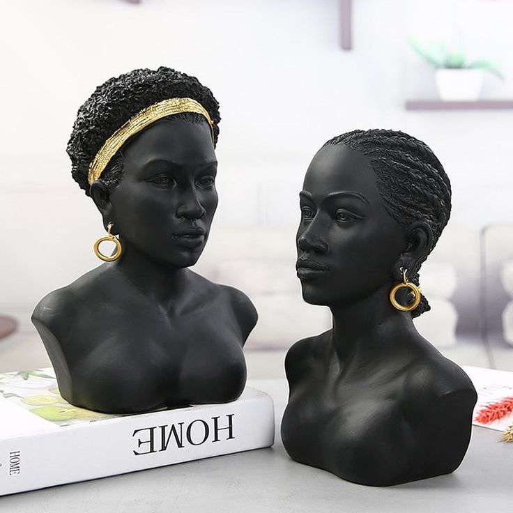 two black mannequins are sitting next to each other on top of a book