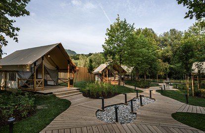 a wooden walkway leading to two cabins in the woods