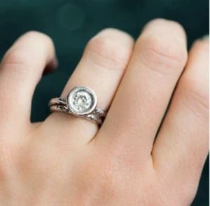 a woman's hand wearing a ring with a diamond on the middle and side