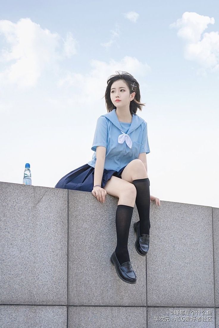 a woman sitting on top of a cement wall