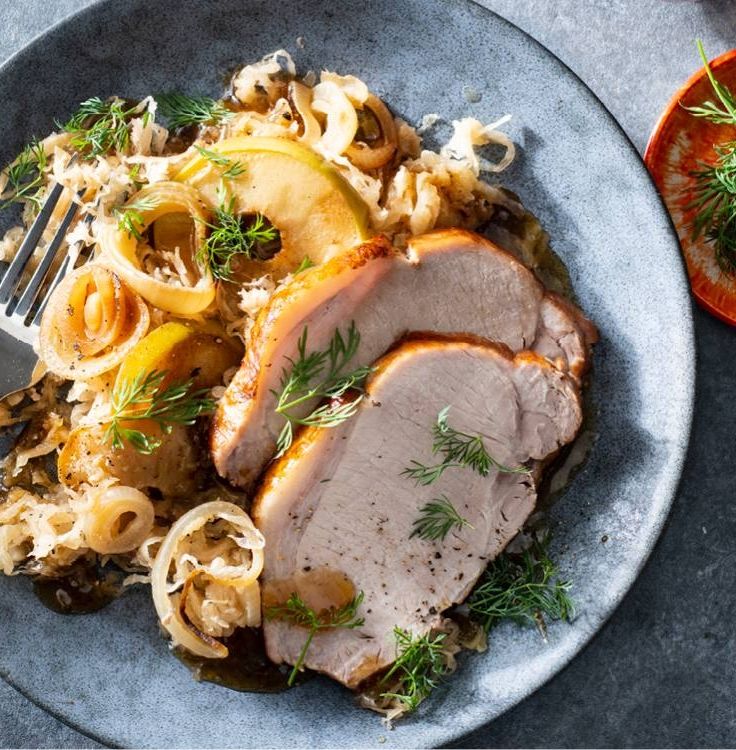 a blue plate topped with meat and onions next to an orange slice on top of a table