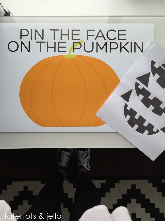 a person standing in front of a sign that says pin the face on the pumpkin