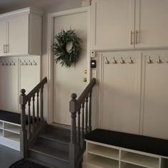 an entry way with white cabinets and stairs