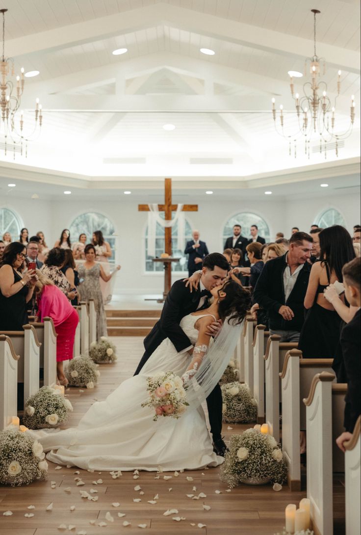 a bride and groom kissing in front of the alter at a wedding ceremony with confetti falling from the pews