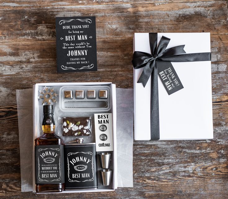 an open gift box with liquor bottles and a bottle of whiskey next to it on top of a wooden table