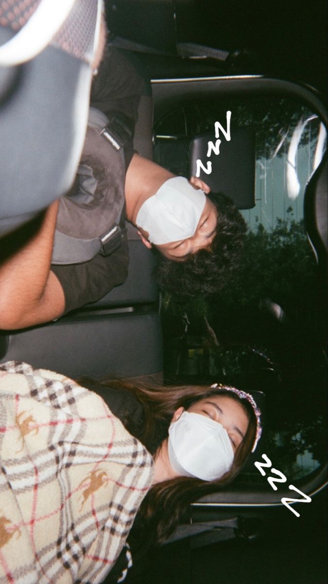 two people wearing face masks in the back of a car